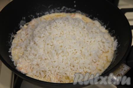 Всыпать варёный рис в сковороду с креветками и сливочным соусом.
