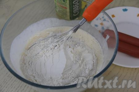 Начать частями всыпать муку, каждый раз очень хорошо перемешивая тесто для оладий венчиком.