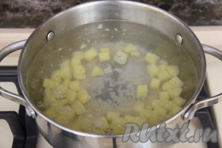 Влить в кастрюлю 1,5 литра воды, поставить на огонь. В кастрюлю с закипевшей водой добавить рис и картошку, нарезанную на средние кубики.