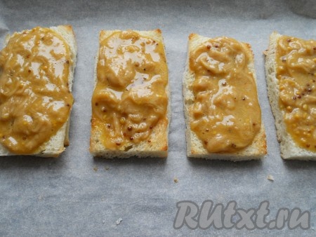 Смазать ломти хлеба сырной массой сверху, поместить их на противень и отправить в разогретую до 180-190 градусов духовку на 7-10 минут.