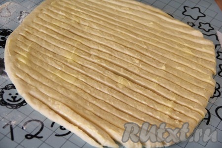 Затем разрезать тесто на полоски шириной примерно 1 сантиметр, не дорезая полоски с одного края до конца.